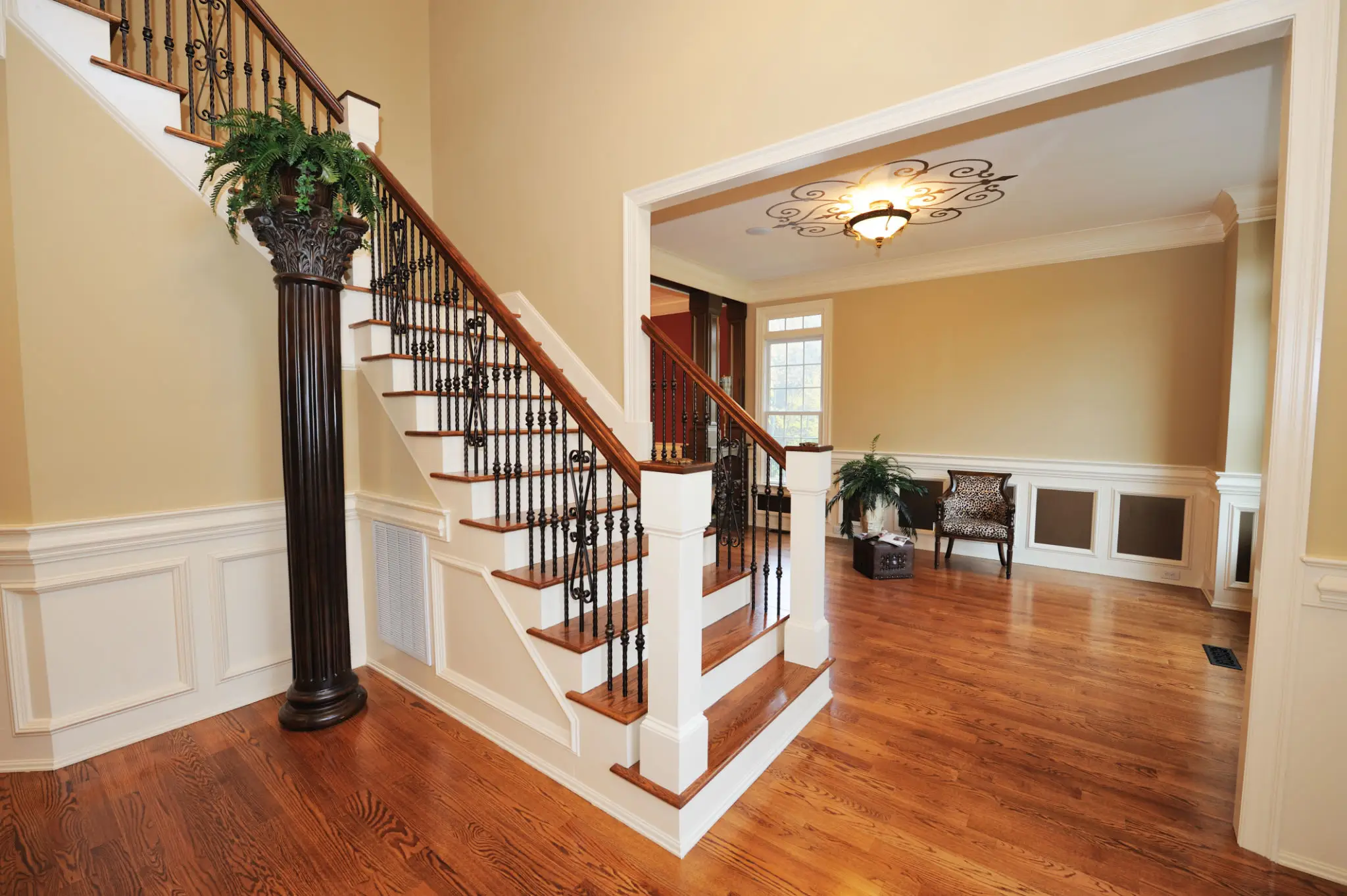 Elegant staircase with wooden steps and wrought iron balusters in a bright home.